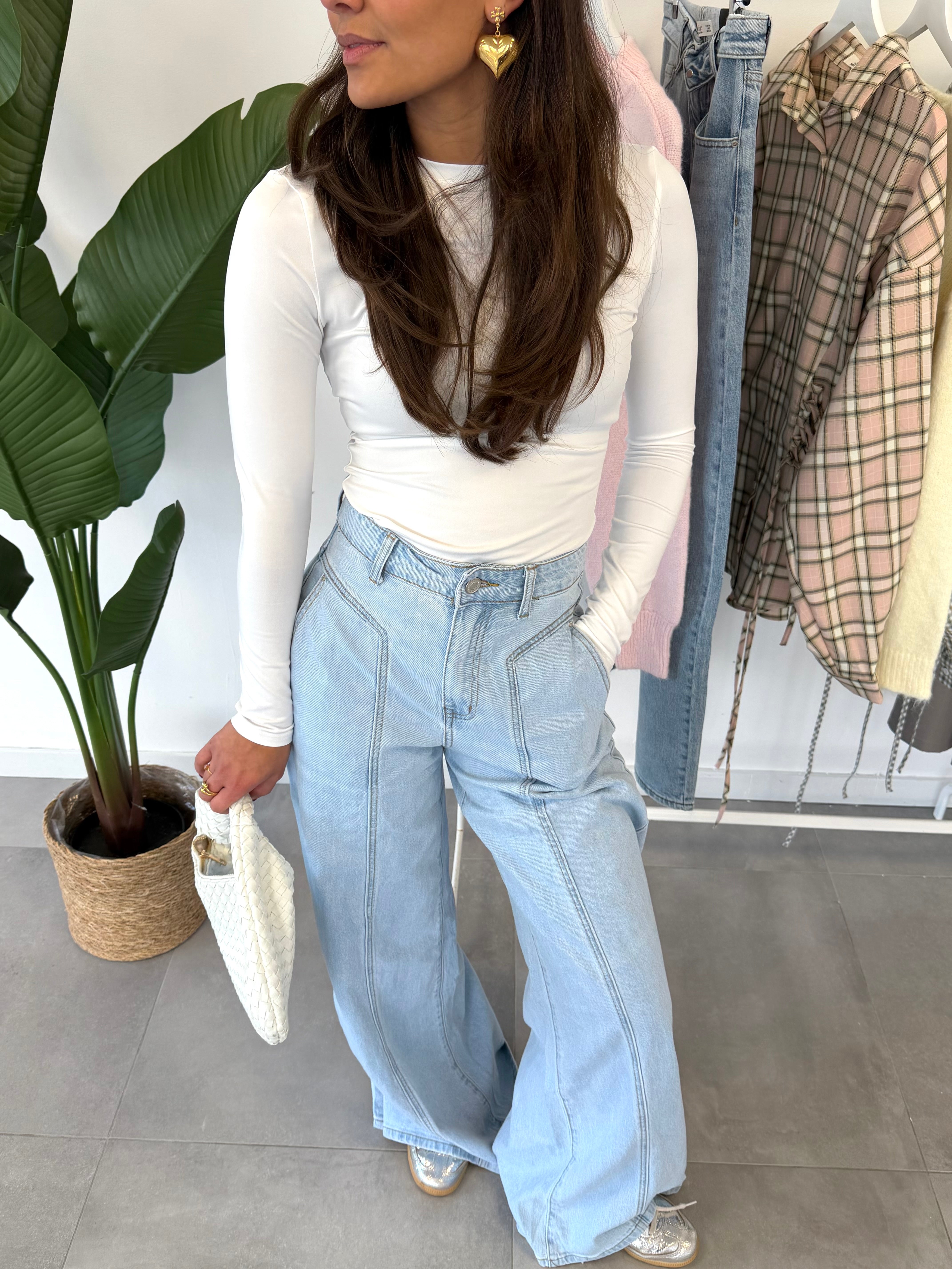 Fiora jeans – wijdvallende broek met subtiele streepdessin als detail, gecombineerd met een witte longsleeve, close-up vooraanzicht