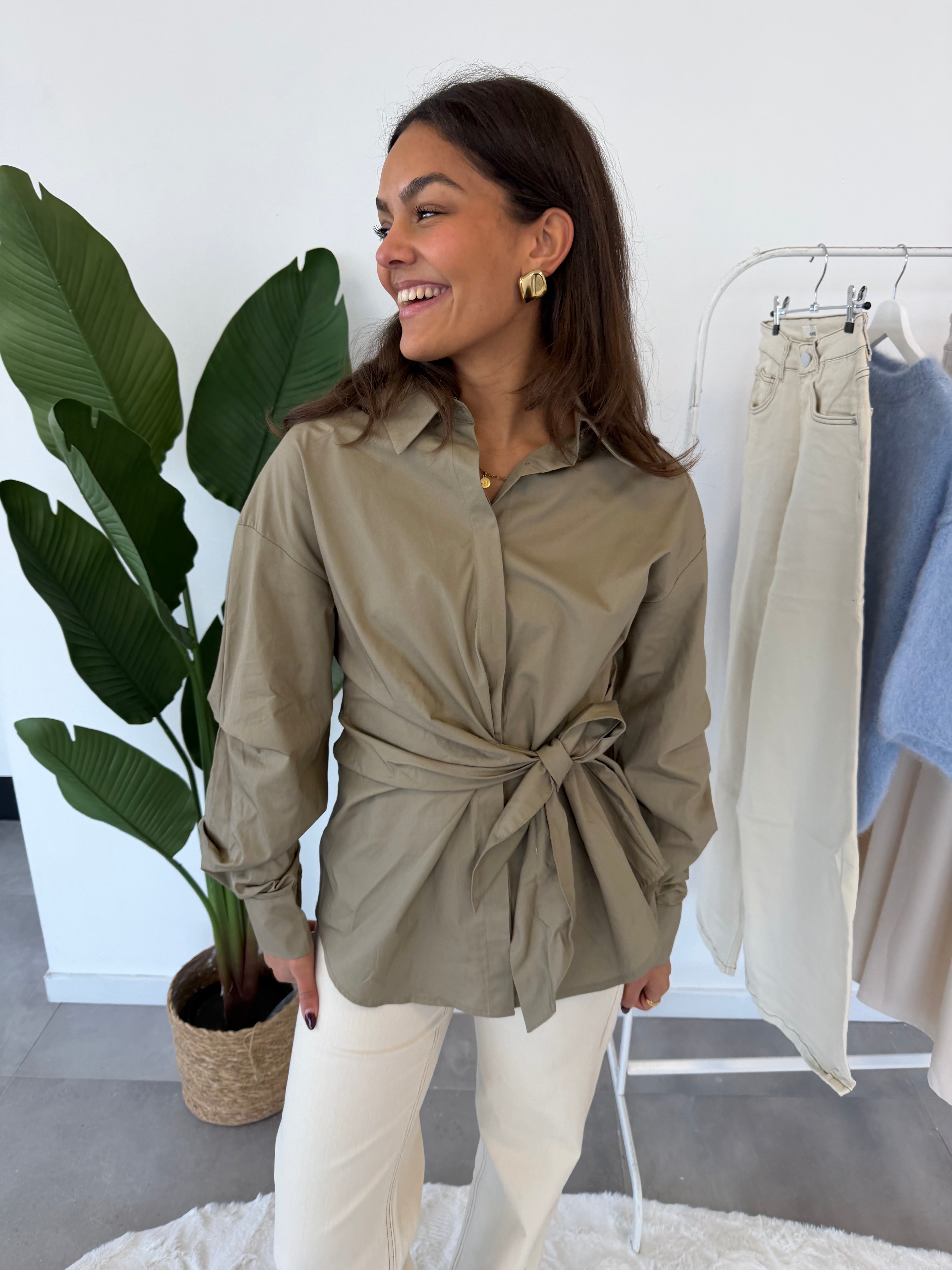 Sivah blouse – taupe dames blouse met strikdetail, licht zijaanzicht en glimlachende look